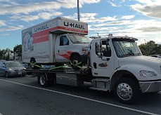 SafeTow flatbed carrying a loaded U-Haul moving truck